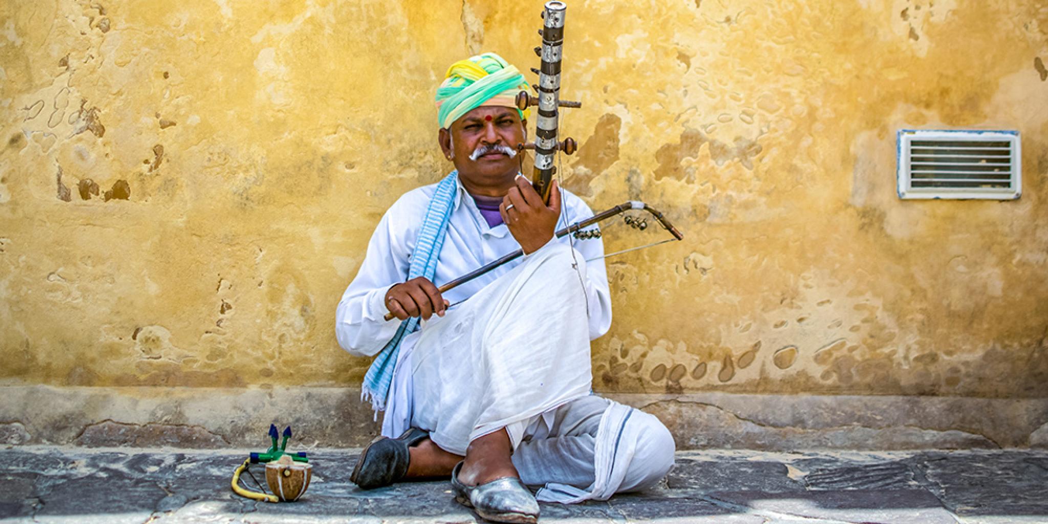 Man with string instrument and yellow wall