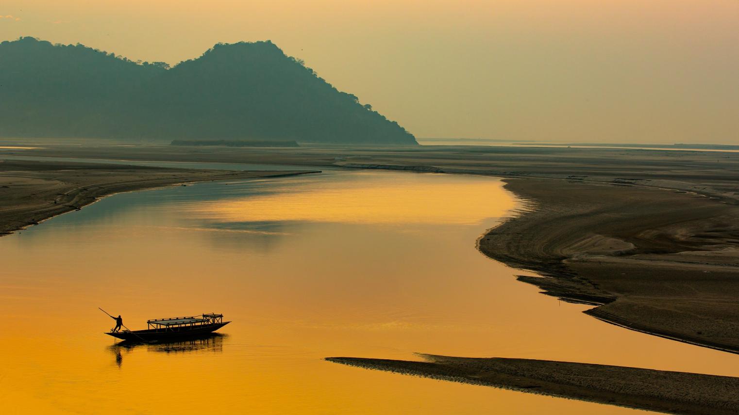 Sunset on the river,silhouette of a man rowing a boat, Mayong, Brahmaputra river, Assam, India; Photo By Jimmy Kamballur